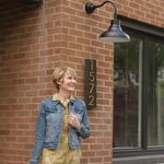 Black outdoor lighting by Post & Porch, home of curb appeal accessories for the front porch and beyond; Pictured with woman and address plaque