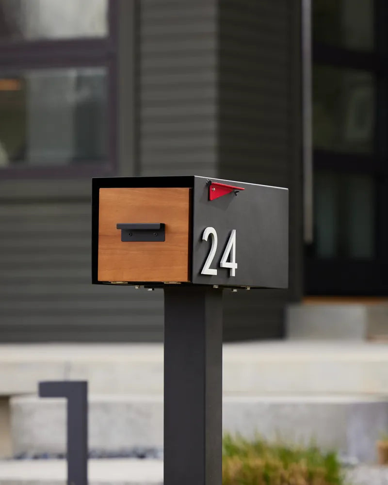 The Malone with a wood door and house number 24 in front of a dark modern home