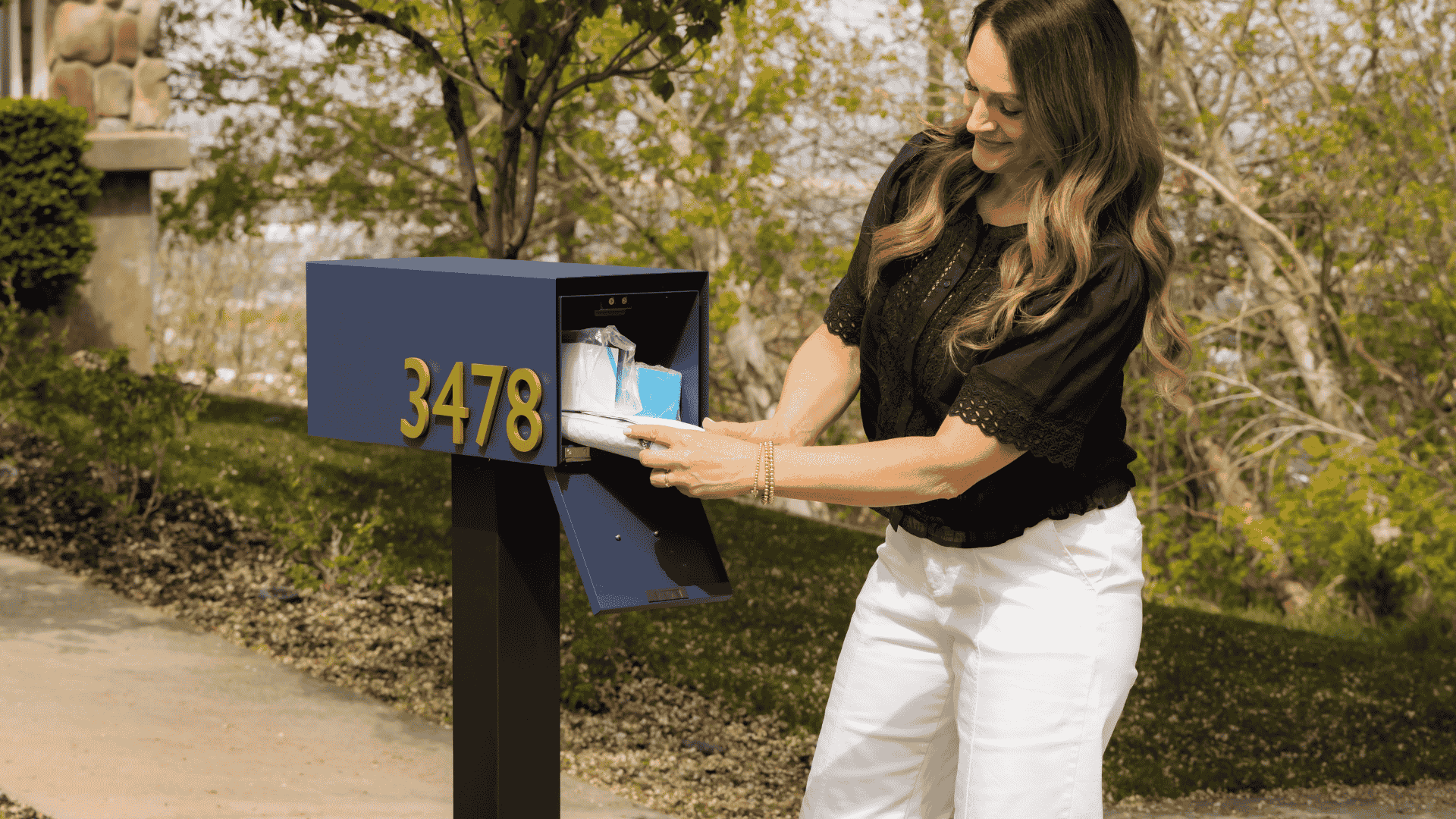 Woman interacting with a modern rear-access mailbox outdoors